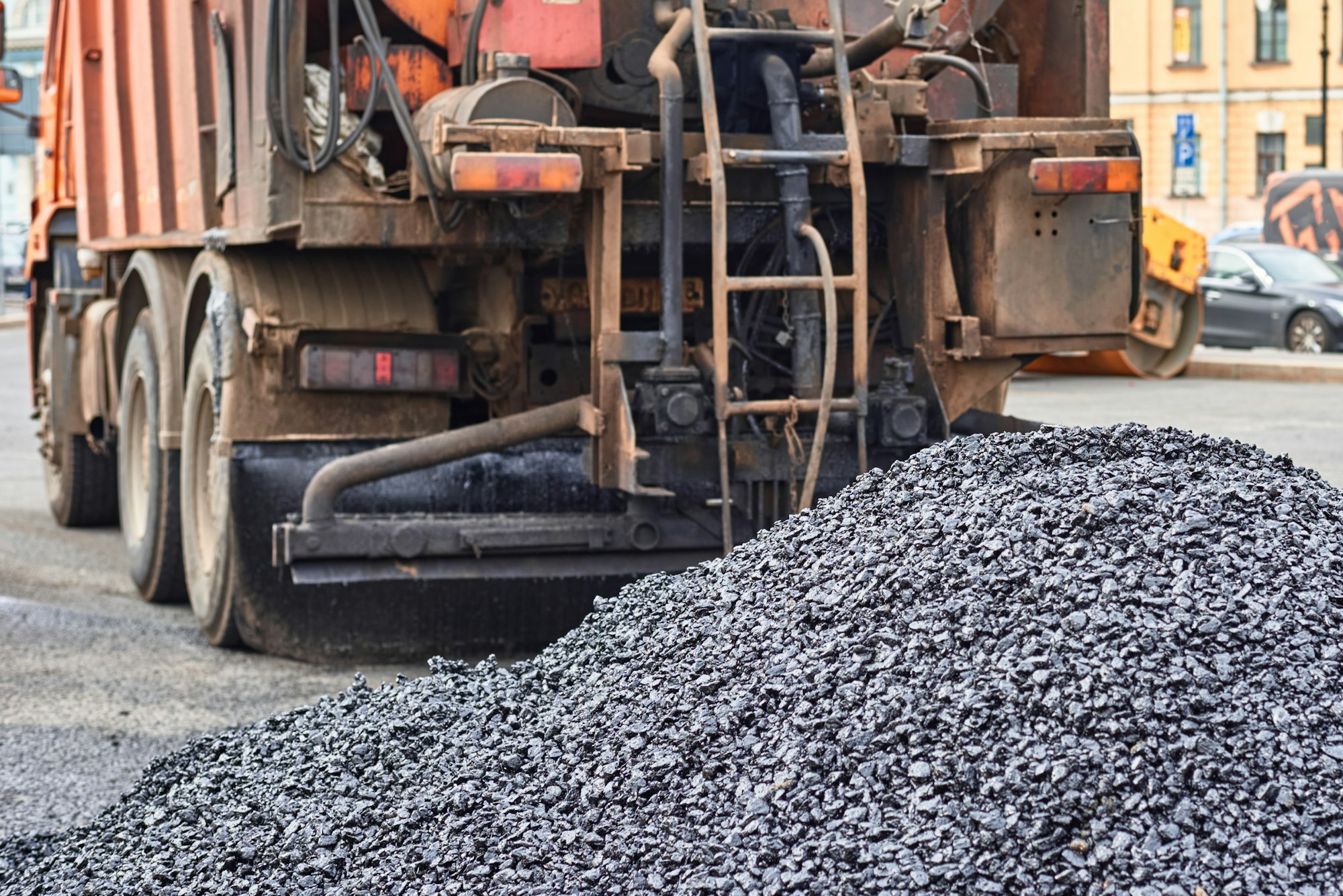 Hot asphalt and trick with a bitumen in city. Road construction